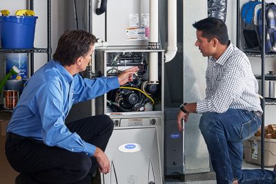 65df8c11f3e4c468cbd351a5_furnace repair vs replacement – Copy HVAC technician explaining furnace repair and maintenance to a homeowner in San Tan Valley, AZ